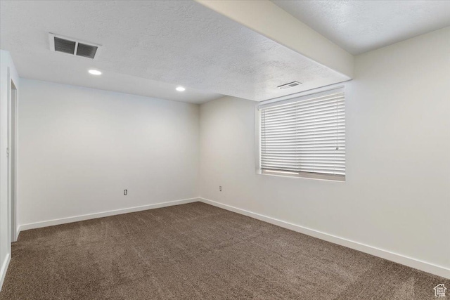 carpeted spare room with baseboards, a textured ceiling, and visible vents