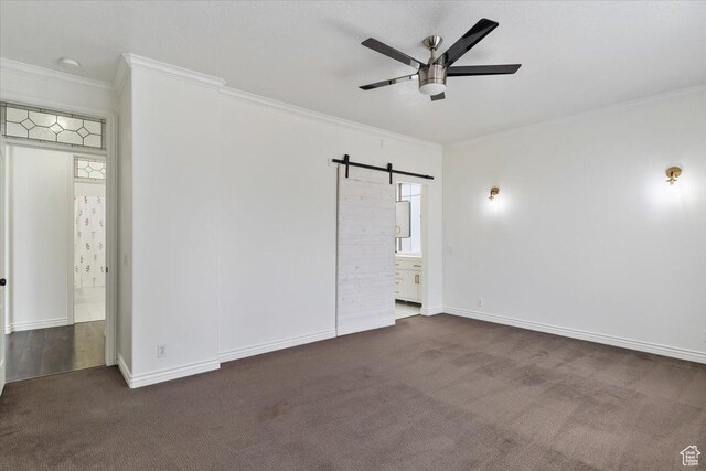 spare room with carpet flooring, ornamental molding, and a barn door
