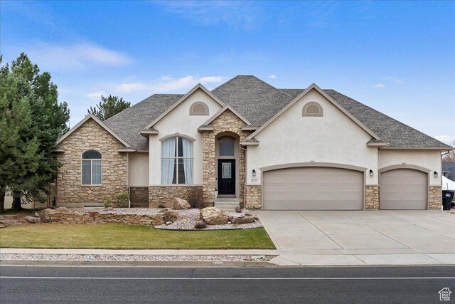 view of front of home featuring stone siding, stucco siding, roof with shingles, and an attached garage