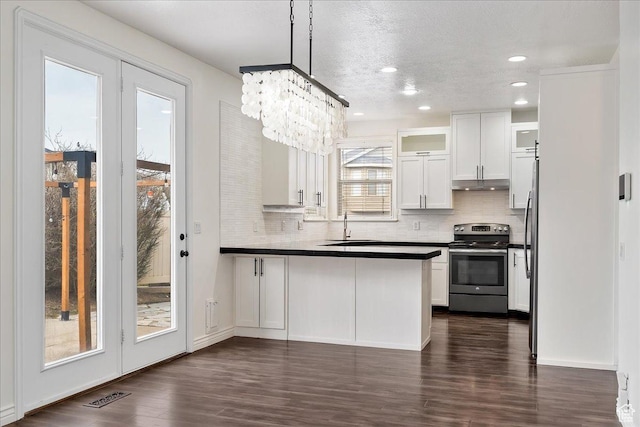 kitchen featuring visible vents, dark countertops, stainless steel electric range, under cabinet range hood, and a sink