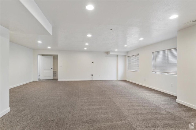 carpeted empty room with visible vents, a textured ceiling, baseboards, and recessed lighting