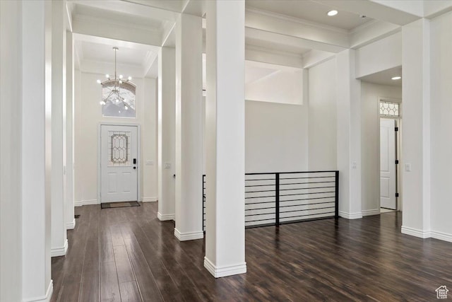 foyer entrance featuring dark wood-style flooring, crown molding, baseboards, recessed lighting, and an inviting chandelier