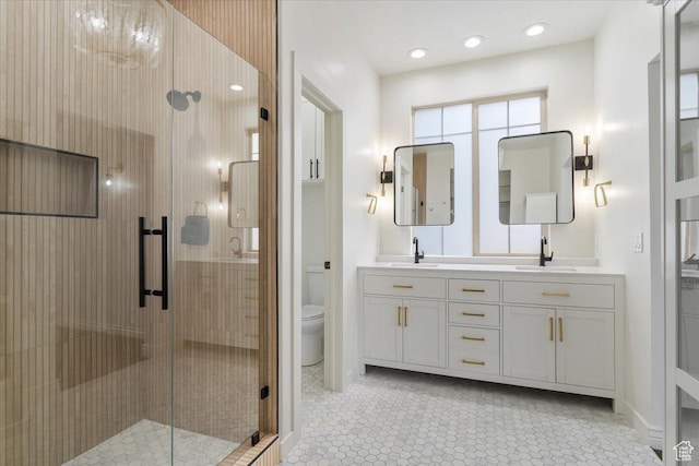full bathroom featuring a stall shower, double vanity, toilet, and a sink