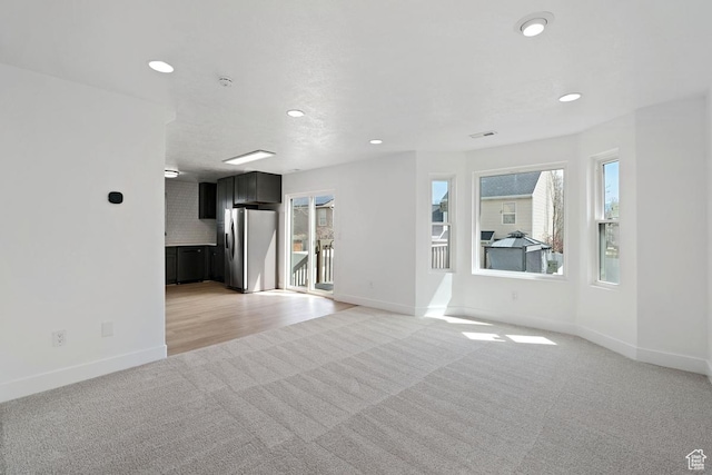 unfurnished living room featuring light colored carpet, recessed lighting, and baseboards