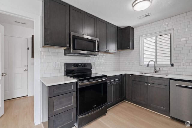 kitchen featuring light countertops, visible vents, light wood-style flooring, stainless steel appliances, and a sink