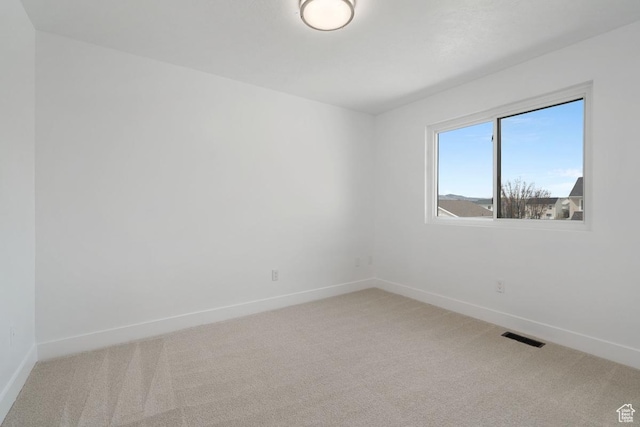 empty room with light colored carpet, visible vents, and baseboards