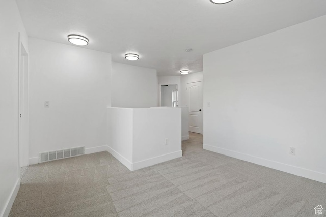 carpeted empty room featuring baseboards and visible vents