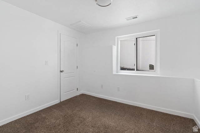 empty room with baseboards, visible vents, and dark carpet