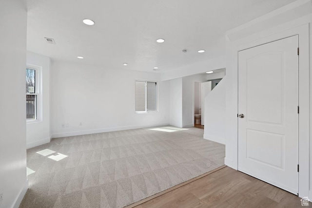 unfurnished room featuring visible vents, light wood-style flooring, baseboards, recessed lighting, and light carpet