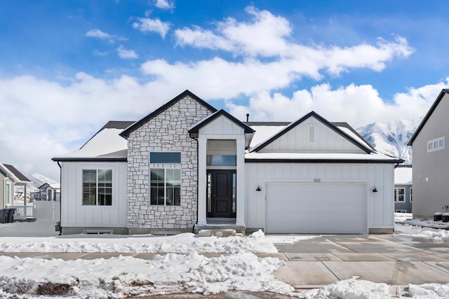 modern farmhouse style home with stone siding, board and batten siding, driveway, and a garage