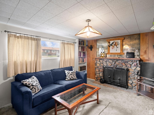 carpeted living area featuring wood walls and a fireplace