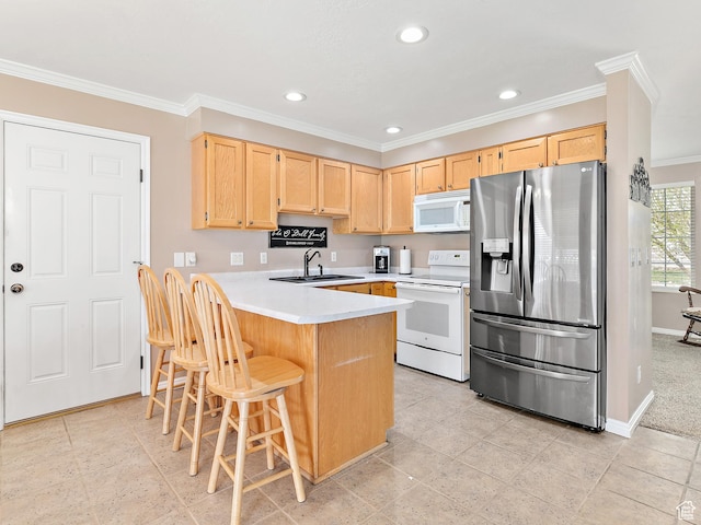 kitchen with light countertops, a peninsula, white appliances, a sink, and light brown cabinetry