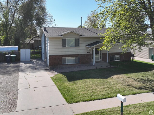 raised ranch featuring brick siding and roof with shingles
