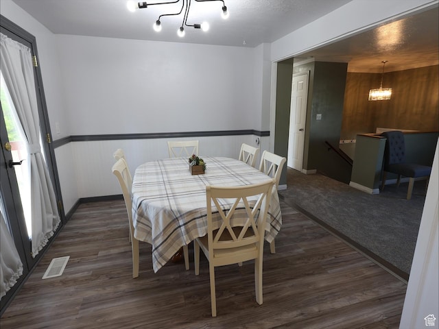 dining space with a chandelier, dark wood finished floors, and baseboards