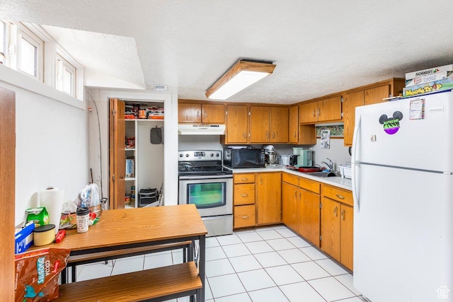 67 N 200 E, Tremonton, UT 84337 - kitchen featuring stainless steel electric range, under cabinet range hood, black microwave, brown cabinetry, and freestanding refrigerator