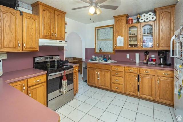 67 N 200 E, Tremonton, UT 84337 - kitchen with stainless steel appliances, under cabinet range hood, arched walkways, ceiling fan, and brown cabinetry