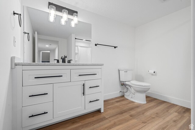 full bath with baseboards, toilet, vanity, and wood finished floors