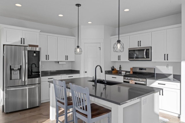 kitchen with a sink, stainless steel appliances, dark countertops, and wood finished floors