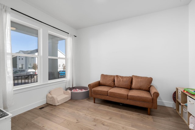 sitting room with baseboards, light wood-type flooring, and visible vents