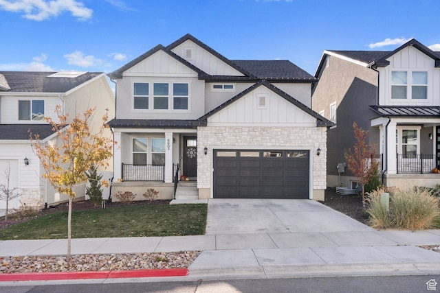 view of front of property with a front yard, stone siding, concrete driveway, board and batten siding, and a garage