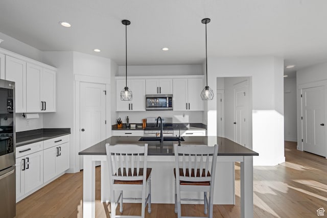 kitchen featuring dark countertops, light wood-style floors, a sink, and stainless steel microwave