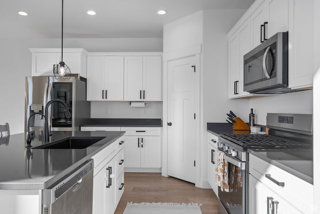 kitchen with white cabinetry, recessed lighting, a sink, light wood-style flooring, and appliances with stainless steel finishes