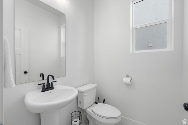 bathroom featuring toilet, a sink, and baseboards