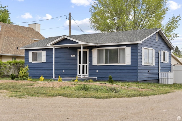 view of front of home featuring a shingled roof, fence, and a chimney
