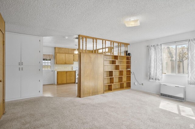 67 W 300 S, Kanab, UT 84741 - unfurnished living room featuring a textured ceiling, heating unit, a wealth of natural light, and light colored carpet