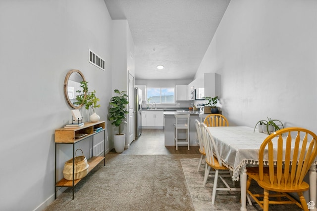 dining area with a textured ceiling, baseboards, and visible vents