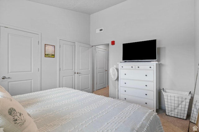 bedroom with a closet, vaulted ceiling, visible vents, and carpet flooring