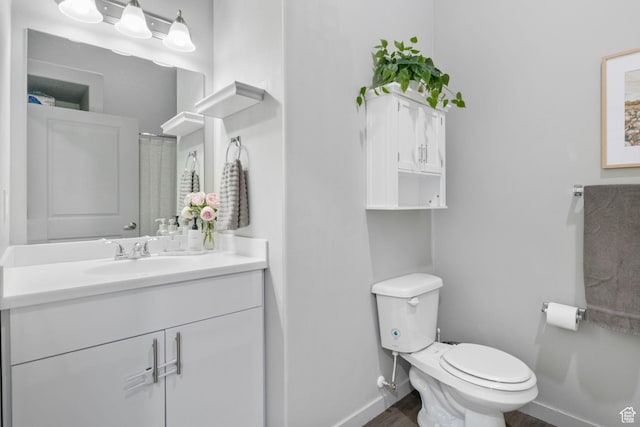 bathroom with baseboards, toilet, vanity, and wood finished floors
