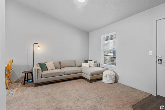 carpeted living room featuring baseboards and lofted ceiling