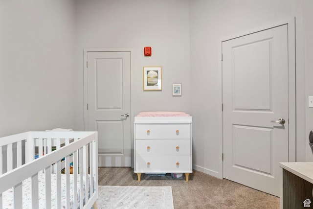 bedroom featuring light carpet, baseboards, and a nursery area