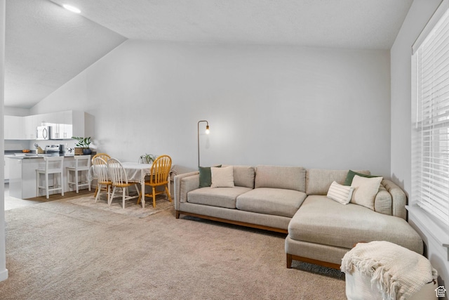 living area featuring high vaulted ceiling and light colored carpet