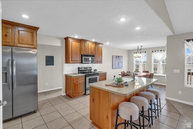 2367 N Monarch Cir E, Cedar City, UT 84721 - kitchen with stainless steel appliances, light tile patterned flooring, baseboards, light countertops, and a kitchen breakfast bar