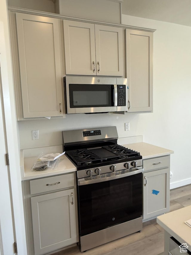 kitchen with baseboards, light countertops, light wood-style floors, and stainless steel appliances