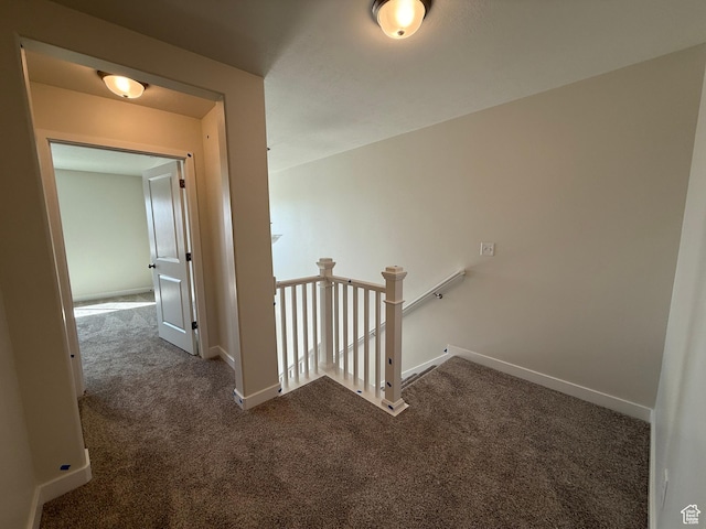 corridor featuring baseboards, an upstairs landing, and carpet floors
