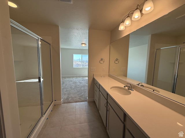 full bathroom featuring a stall shower, vanity, a textured ceiling, tile patterned flooring, and visible vents