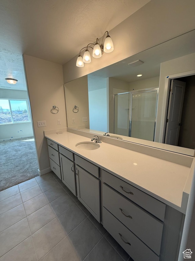 full bathroom featuring a stall shower, baseboards, tile patterned flooring, and vanity