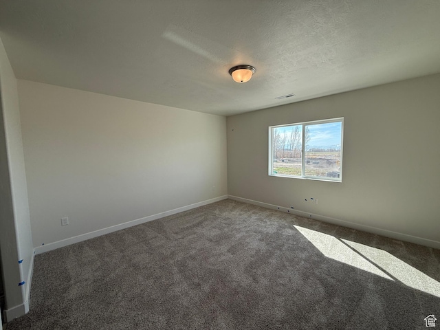 carpeted empty room featuring baseboards, visible vents, and a textured ceiling