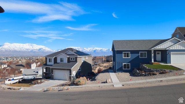 view of front of home with a residential view, concrete driveway, and a mountain view