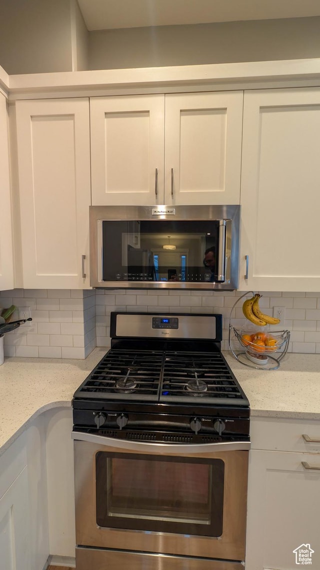 kitchen featuring white cabinetry, light stone countertops, tasteful backsplash, and appliances with stainless steel finishes