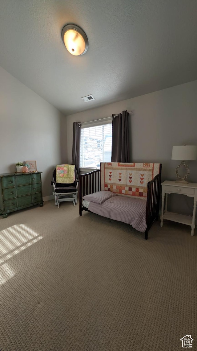 carpeted bedroom featuring lofted ceiling, a textured ceiling, and visible vents