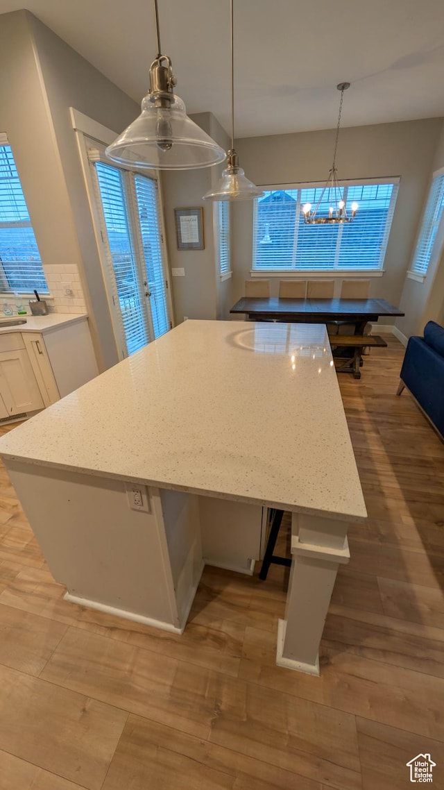 kitchen featuring pendant lighting, white cabinetry, light wood-style floors, and a kitchen island