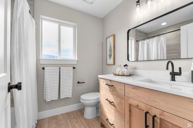 full bath featuring toilet, wood finished floors, vanity, and baseboards