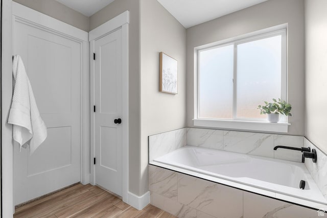 full bathroom featuring a garden tub and wood finished floors