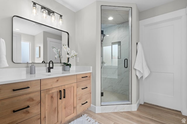 full bathroom featuring vanity, a marble finish shower, and wood finished floors