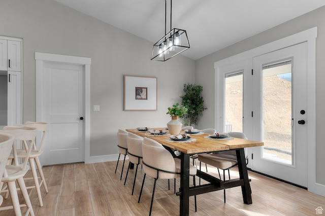 dining space with light wood-style flooring, baseboards, and lofted ceiling