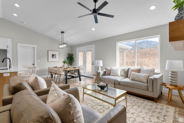 living room featuring light wood finished floors, recessed lighting, lofted ceiling, and a wealth of natural light